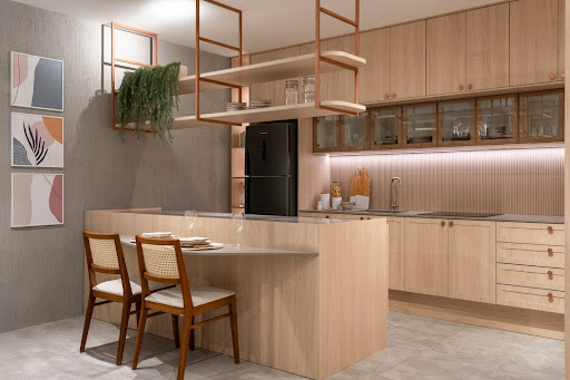 Cozinha pequena com móveis em madeira clara, bancada com duas cadeiras, prateleiras suspensas com plantas e utensílios, iluminação embutida e eletrodomésticos em preto.