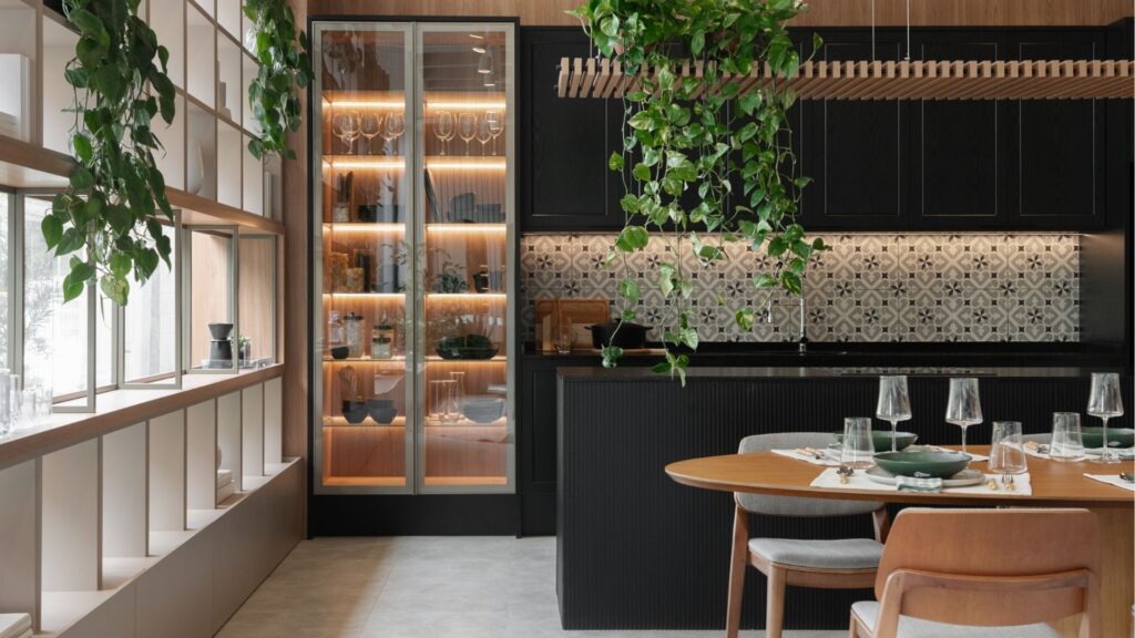 Uma cozinha moderna e bem decorada, com móveis sob medida, incluindo armários e prateleiras personalizadas, que se adaptam perfeitamente ao ambiente. O design elegante e funcional, com iluminação embutida e acabamentos refinados, exemplifica como os móveis sob medida são a escolha ideal para espaços otimizados e com estilo único, adequados às necessidades específicas de cada residência.