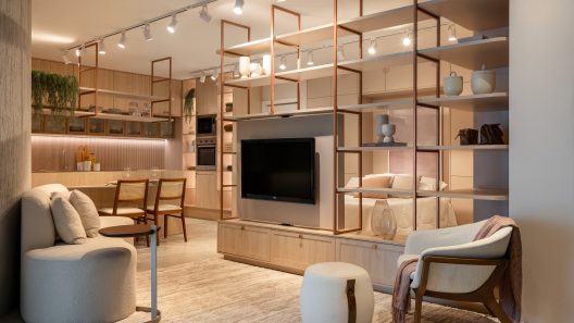 Sala integrada a cozinha e quarto com decoração moderna e estante vazada com TV.