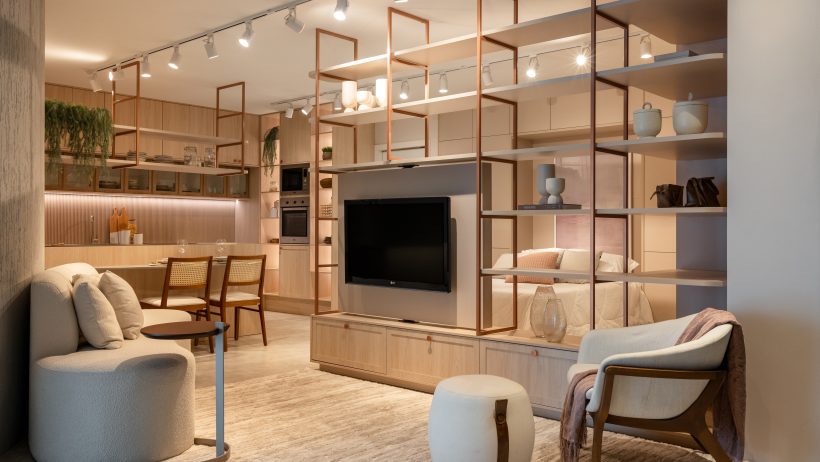 Sala integrada a cozinha e quarto com decoração moderna e estante vazada com TV.