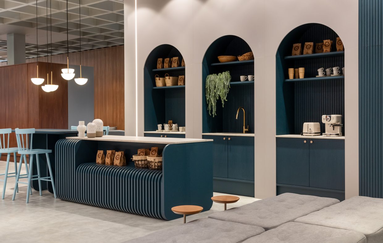 Cafeteria moderna com balcão azul, nichos arqueados, prateleiras decoradas e iluminação pendente.