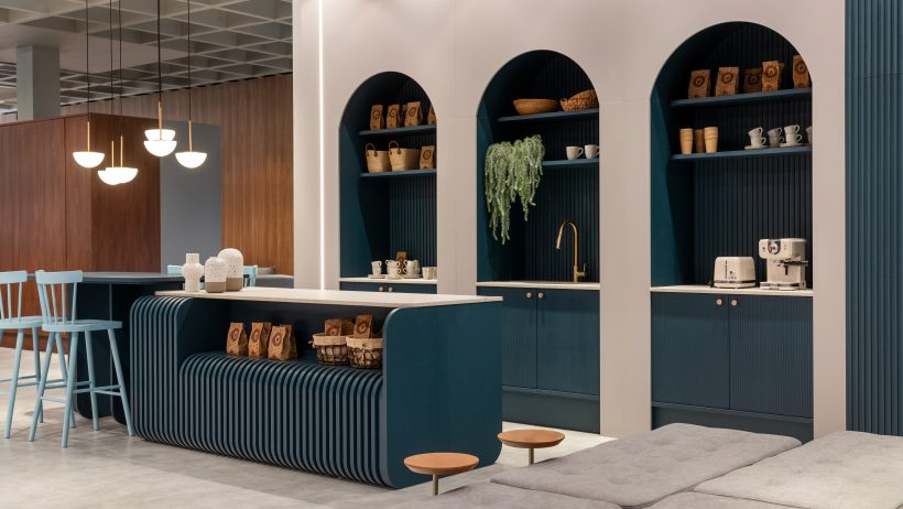 Cafeteria moderna com balcão azul, nichos arqueados, prateleiras decoradas e iluminação pendente.