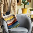 Designer de interiores escolhendo amostras de tecido coloridas sobre poltrona.