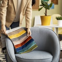 Designer de interiores escolhendo amostras de tecido coloridas sobre poltrona.