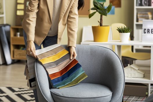 Designer de interiores escolhendo amostras de tecido coloridas sobre poltrona.